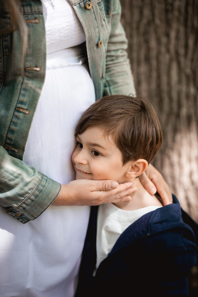 Photographe maternité frère écoutant le ventre de sa maman